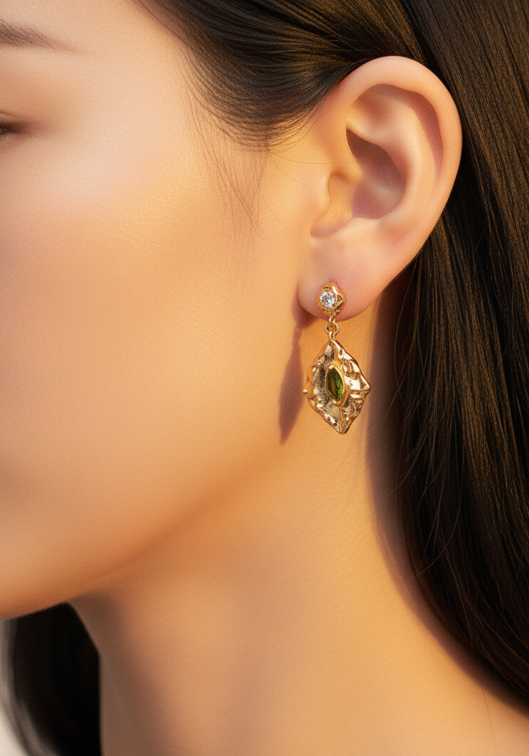 Gold drop earrings worn warm lighting