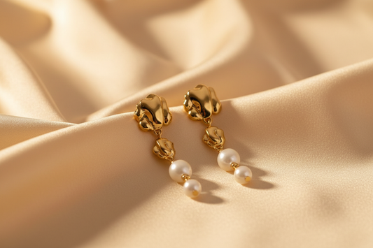 Gold pearl earrings on cream fabric